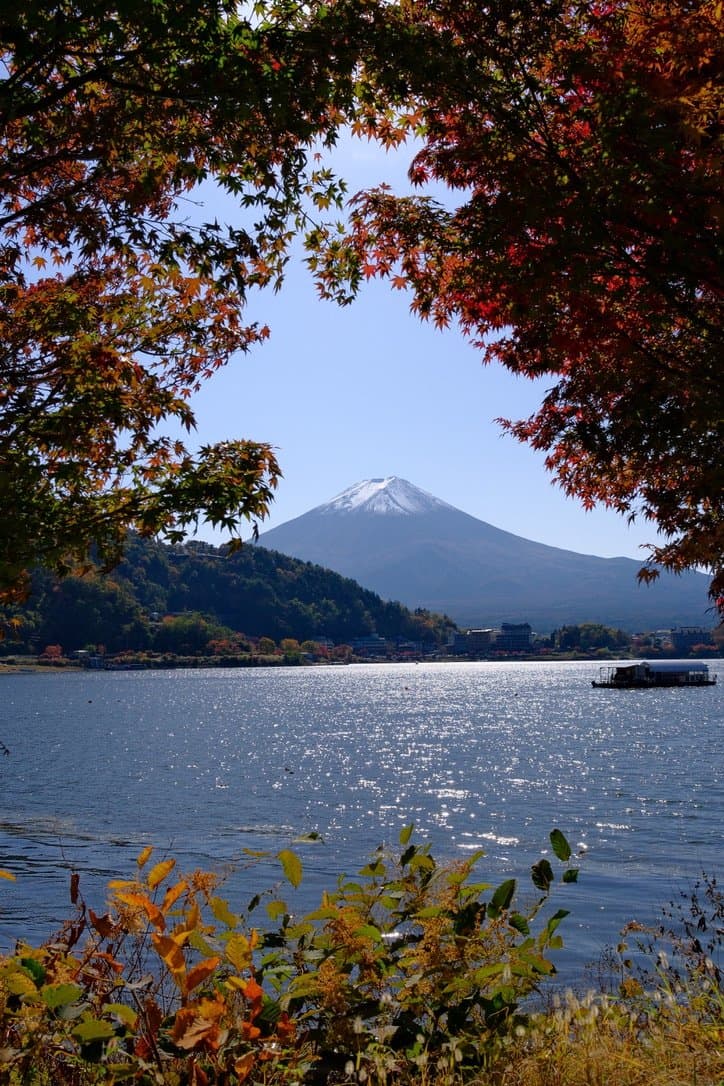 Mount Fuji framed by red and orange maple leaves above Lake Kawaguchiko